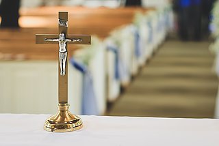 Silberne Jesusfigur auf einem goldenen Kruzifix auf einem Altar in einer leeren Kirche